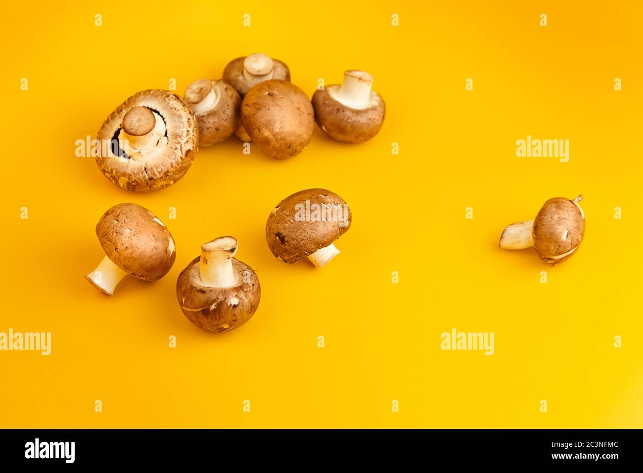 Funghi, champignons marroni freschi sparsi su sfondo giallo. Ingrediente alimentare non fatto a punto, fuoco selettivo Foto Stock
