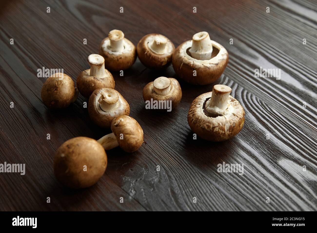 Funghi, gruppo di champignons marroni freschi sparsi su sfondo ligneo. Ingrediente alimentare non fatto a punto, fuoco selettivo Foto Stock