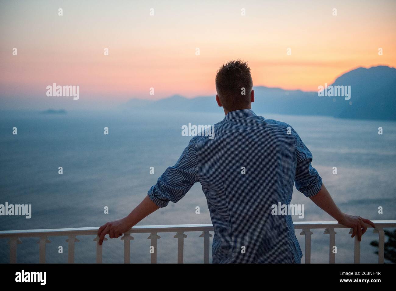 Il turista irriconoscibile gode della vista panoramica al tramonto da Praiano verso Positano. La panoramica costiera amalfitana è una delle principali destinazioni turistiche d'Italia. Foto Stock