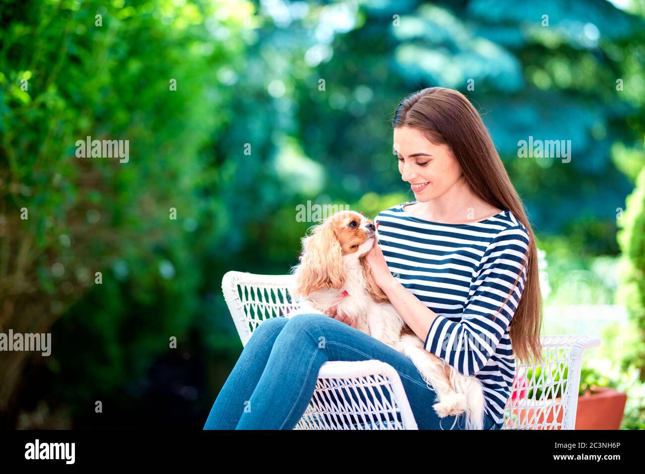 Scatto di donna attraente che si rilassa con il suo cucciolo carino nel giardino a casa. Foto Stock