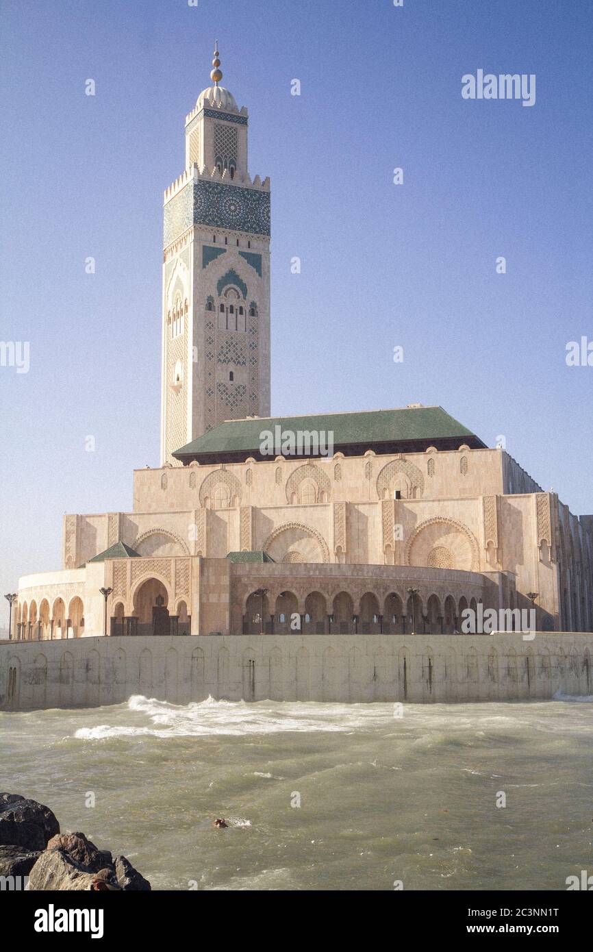 Un uomo che nuota nell'oceano di fronte alla moschea Hassan II a Casablanca, Marocco, durante un pomeriggio in autunno Foto Stock