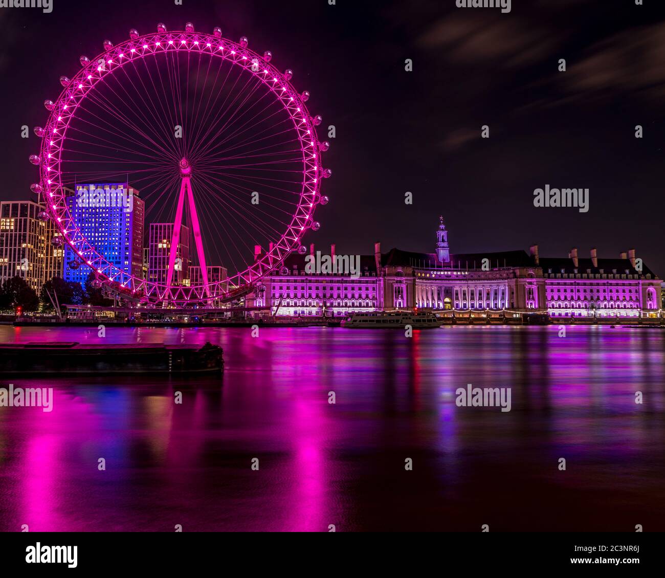 London Eye colore viola dall'altro lato del tamigi, dove si può vedere la County Hall. Foto Stock