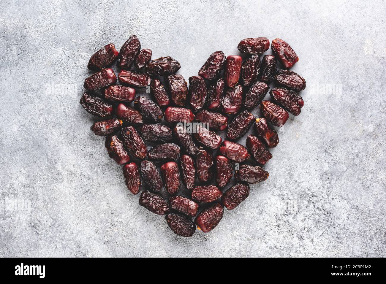 Frutta secca di data su fondo di calcestruzzo in forma di cuore. Cibo vegetariano arabo sano Foto Stock