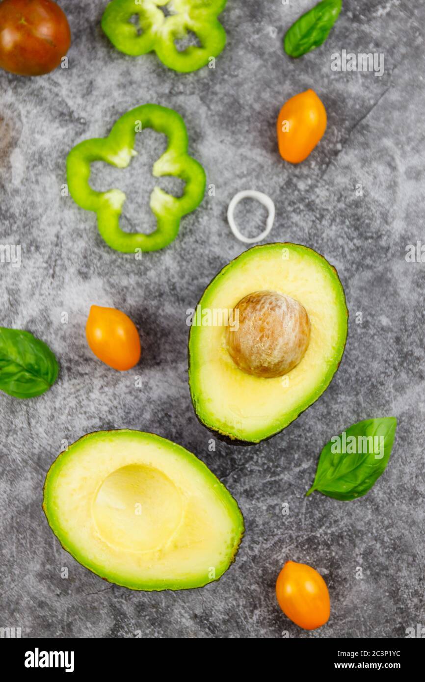 Avocado a metà con fette di lime e foglie di spinaci su un cemento grigio, pietra o sfondo. Vista dall'alto con spazio per la copia. Foto Stock