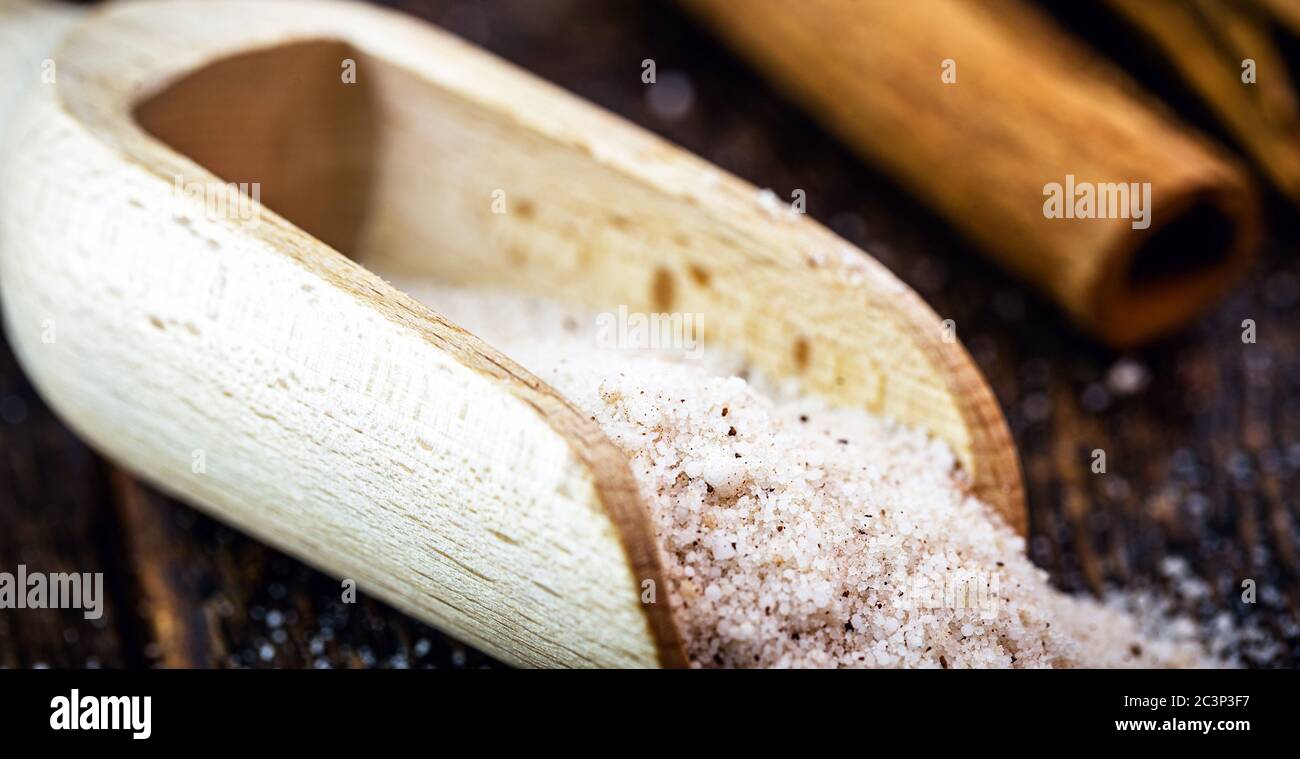misurino in legno con cannella in polvere e zucchero raffinato, utilizzato come ingredienti per dolci e dessert. Foto Stock