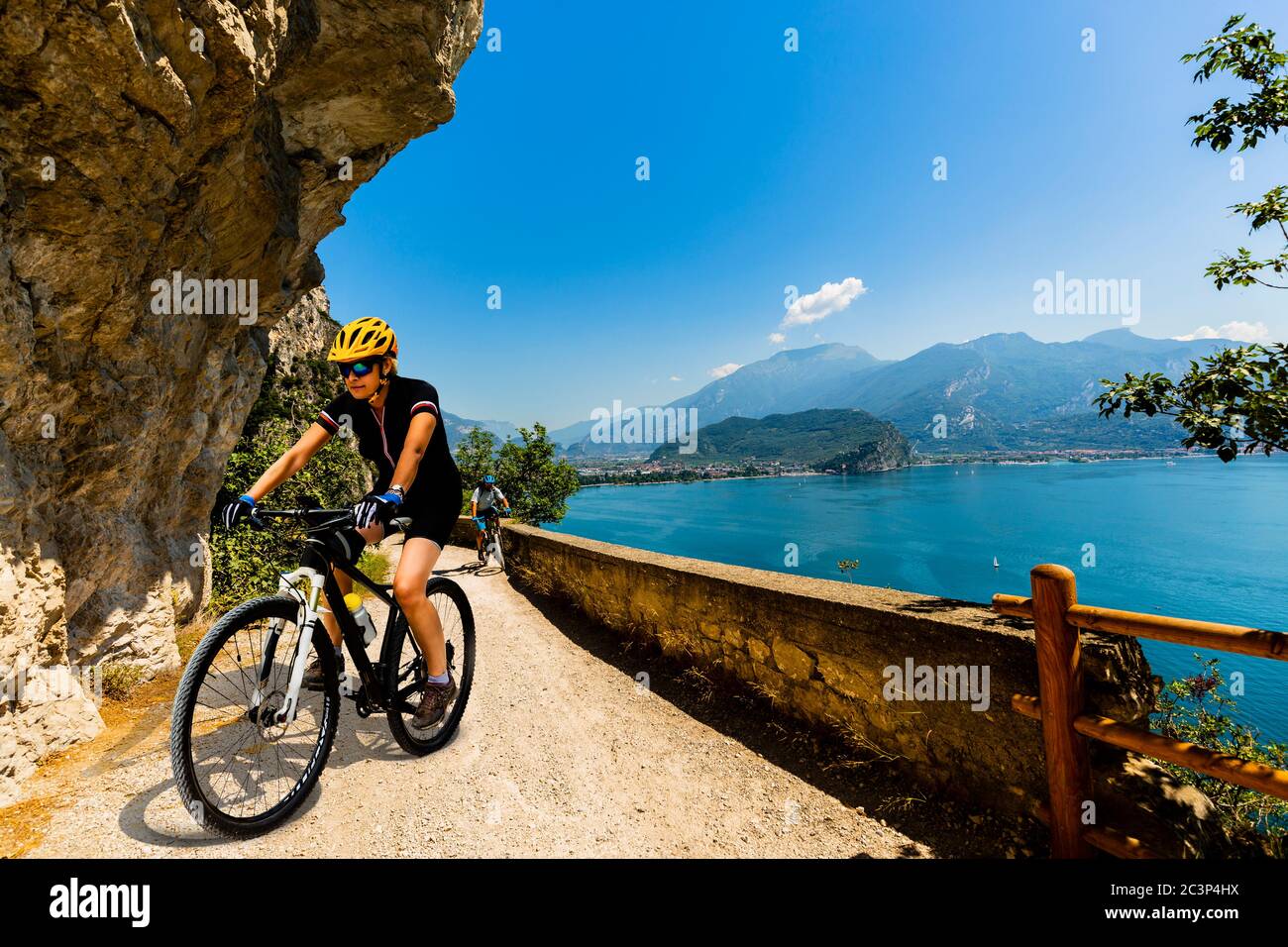Ciclismo donna e uomo in bicicletta in montagna nel paesaggio del lago di Garda. Coppia ciclabile MTB enduro flusso sentiero ponale pista. Sport all'aperto Foto Stock