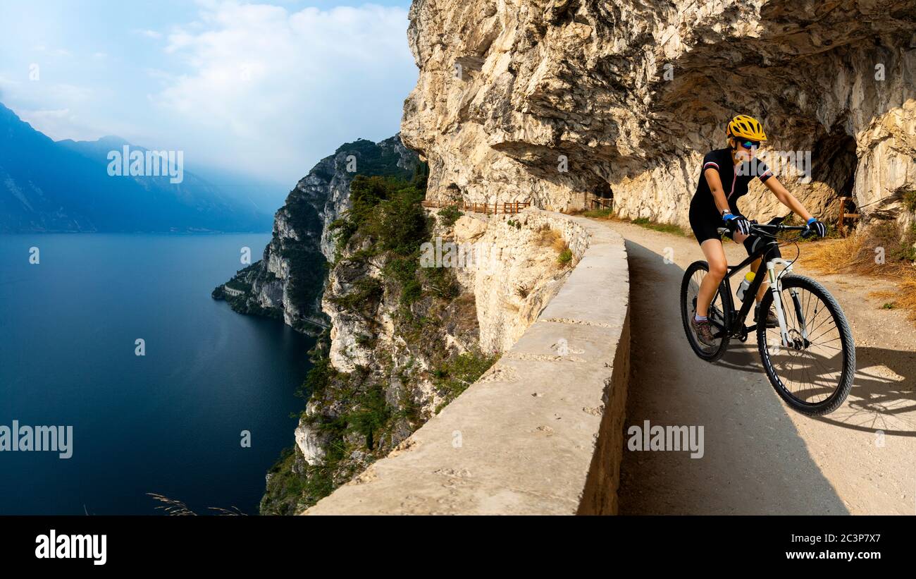 Pedalando uomo in bicicletta sulle montagne dell'alba e sul paesaggio del lago di Garda. Cicloturismo MTB enduro flusso pista sentiero ponale. Attività sportive all'aperto. Foto Stock