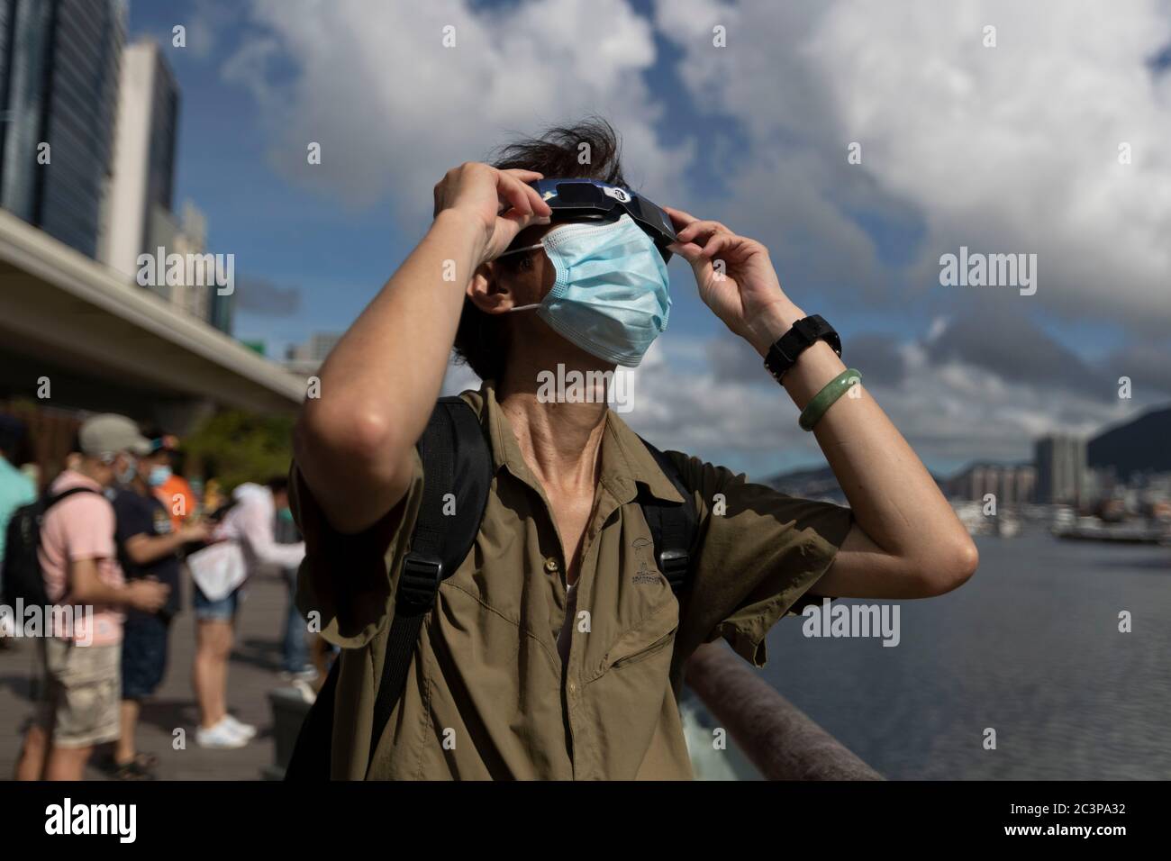 Hong Kong, Cina. 21 Giugno 2020. Un uomo guarda un'eclissi solare parziale anulare attraverso uno speciale visore dell'eclissi lungo una passeggiata a Hong Kong il 21 giugno 2020. Un'eclissi solare parziale si verifica quando una parte della Terra è ingolfata dall'ombra (penombra) gettata dalla Luna mentre passa tra il nostro pianeta e il Sole in un allineamento imperfetto. Durante questa eclissi anulare Ã il primo del decennio Ã la Luna sembra coprire il Sole, lasciando l'alone del Sole come un bordo visibile formando un anello, popolarmente noto come 'anello di credito fuoco: James James maggio / FILO ZUMA / Alamy Live News Foto Stock