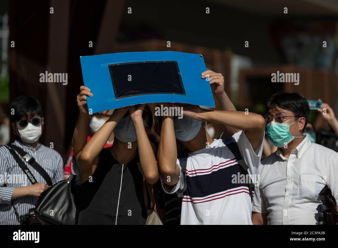 Hong Kong, Cina. 21 Giugno 2020. La gente guarda un'eclissi solare parziale anulare attraverso uno speciale visore dell'eclissi lungo una passeggiata a Hong Kong il 21 giugno 2020. Un'eclissi solare parziale si verifica quando una parte della Terra è ingolfata dall'ombra (penombra) gettata dalla Luna mentre passa tra il nostro pianeta e il Sole in un allineamento imperfetto. Durante questa eclissi anulare Ã il primo del decennio Ã la Luna sembra coprire il Sole, lasciando l'alone del Sole come un bordo visibile formando un anello, popolarmente noto come 'anello di credito fuoco: James James maggio / FILO ZUMA / Alamy Live News Foto Stock