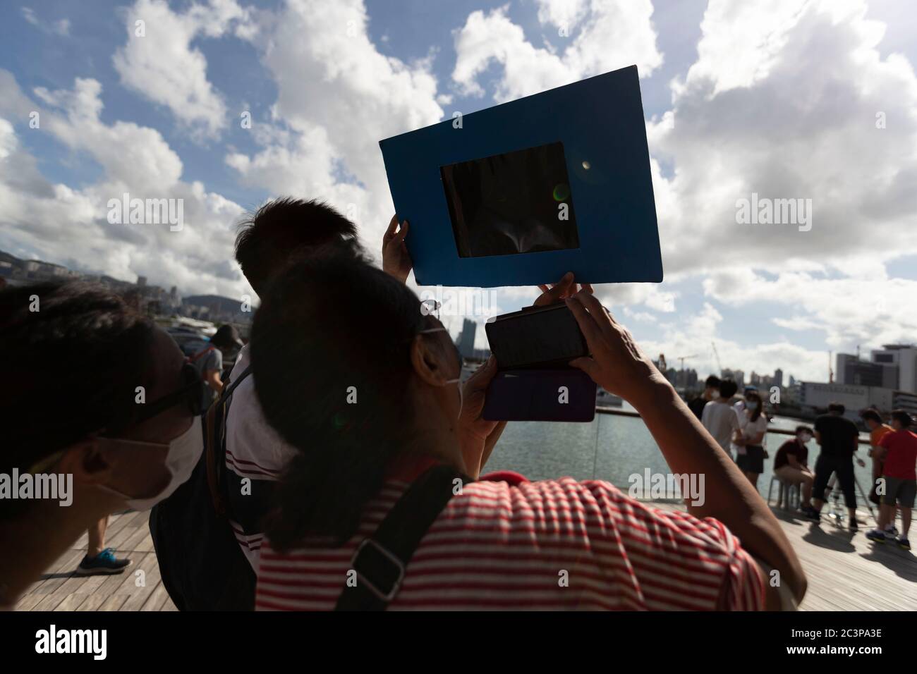 Hong Kong, Cina. 21 Giugno 2020. La gente guarda un'eclissi solare parziale anulare attraverso uno speciale visore dell'eclissi lungo una passeggiata a Hong Kong il 21 giugno 2020. Un'eclissi solare parziale si verifica quando una parte della Terra è ingolfata dall'ombra (penombra) gettata dalla Luna mentre passa tra il nostro pianeta e il Sole in un allineamento imperfetto. Durante questa eclissi anulare Ã il primo del decennio Ã la Luna sembra coprire il Sole, lasciando l'alone del Sole come un bordo visibile formando un anello, popolarmente noto come 'anello di credito fuoco: James James maggio / FILO ZUMA / Alamy Live News Foto Stock