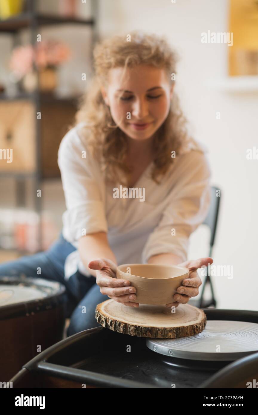 Il vasaio femmina ha finito di fare un vaso di argilla rimuoverlo dalla ruota del vasaio. Creazione vaso di argilla bianca. Produzione di prodotti ceramici da argilla bianca Foto Stock