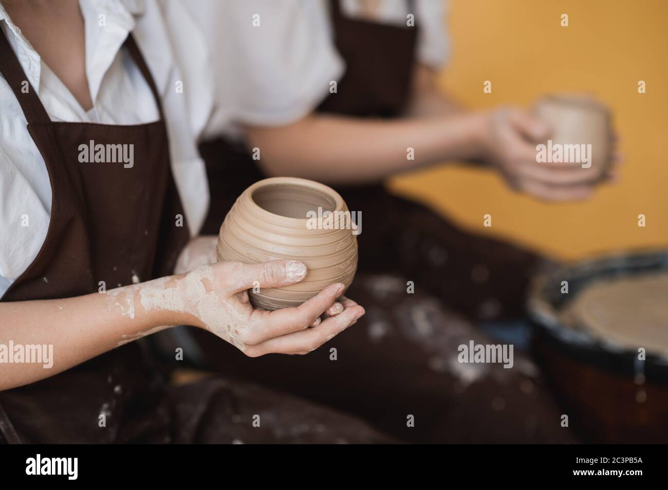 Le vaschette femmina finì di fare un vaso di argilla rimuoverlo dalla ruota del vasaio. Creazione vaso di argilla bianca. Produzione di prodotti ceramici da argilla bianca Foto Stock