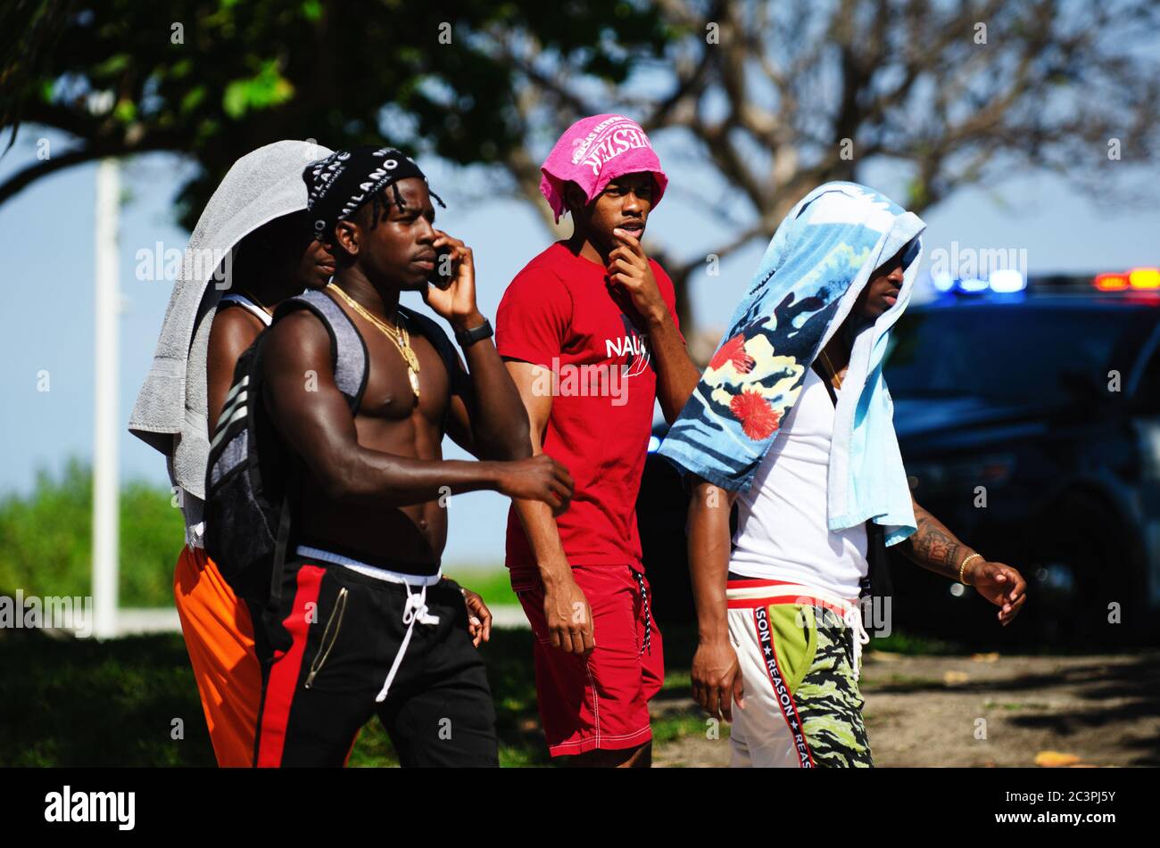 MIAMI - 16 MARZO 2019: I giovani uomini camminano di fronte ad una macchina della polizia che lampeggia luci su Ocean Drive a South Beach durante la vacanza annuale di primavera. Foto Stock MIAMI - 16 MARZO 2019: I giovani uomini camminano di fronte ad una macchina della polizia che lampeggia luci su Ocean Drive a South Beach durante la vacanza annuale di primavera. Foto Stock