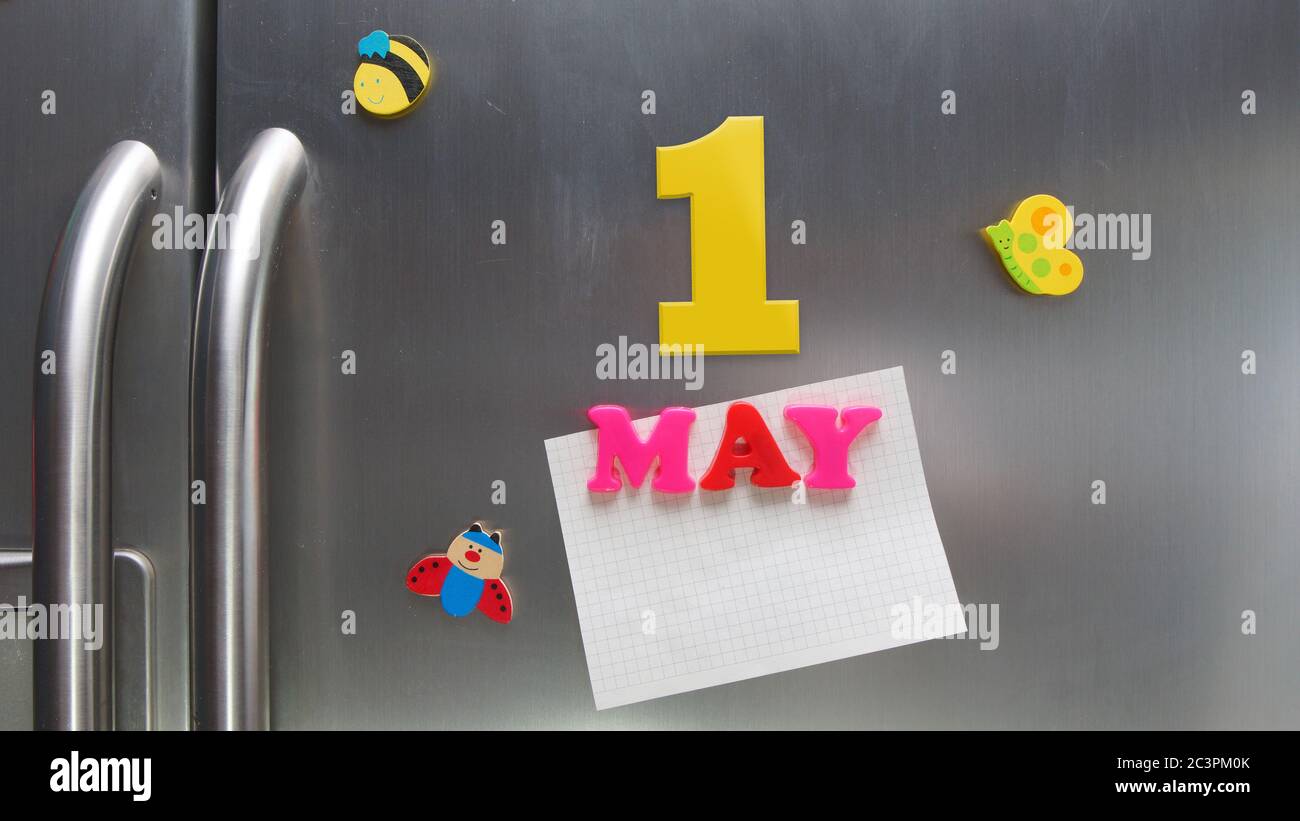 Data di calendario del 1° maggio fatta con lettere magnetiche in plastica che tengono una nota di carta grafica sul frigorifero della porta Foto Stock