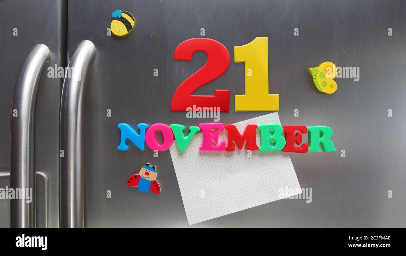 Novembre 21 data di calendario fatta con lettere magnetiche di plastica che tengono una nota di carta grafica sul frigorifero della porta Foto Stock