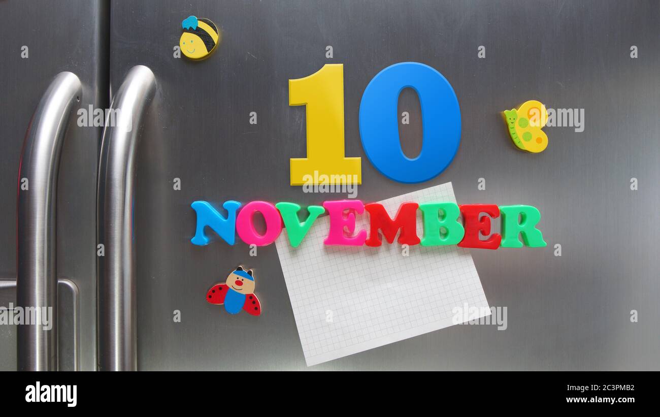 Novembre 10 data di calendario fatta con lettere magnetiche di plastica che tengono una nota di carta grafica sul frigorifero della porta Foto Stock