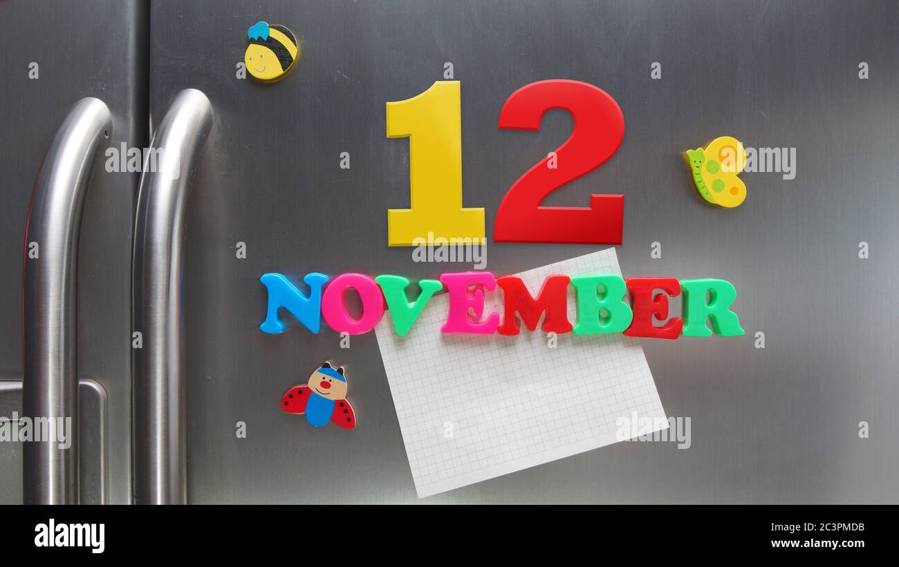 Novembre 12 data di calendario fatta con lettere magnetiche di plastica che tengono una nota di carta grafica sul frigorifero della porta Foto Stock