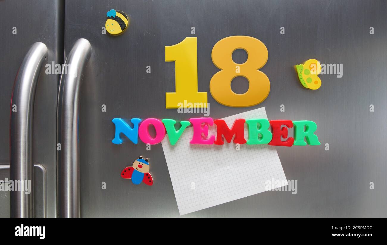 Novembre 18 data di calendario fatta con lettere magnetiche di plastica che tengono una nota di carta grafica sul frigorifero della porta Foto Stock