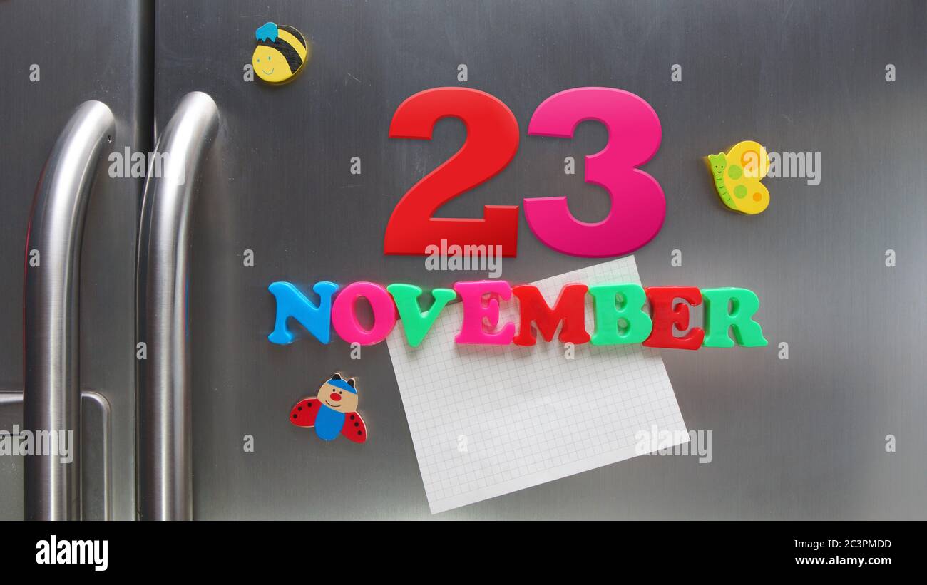 Novembre 23 data di calendario fatta con lettere magnetiche di plastica che tengono una nota di carta grafica sul frigorifero della porta Foto Stock