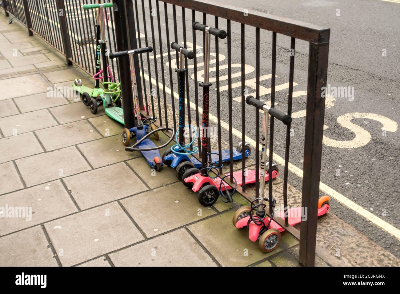 Gli scooter per bambini sono legati fuori dalla scuola, Londra, Regno Unito Foto Stock