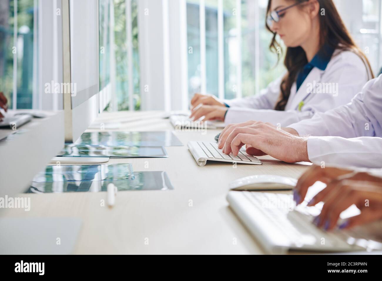 Ricercatori di laboratorio medico che lavorano su computer, inserendo dati e analizzando statistiche e risultati di test medici Foto Stock