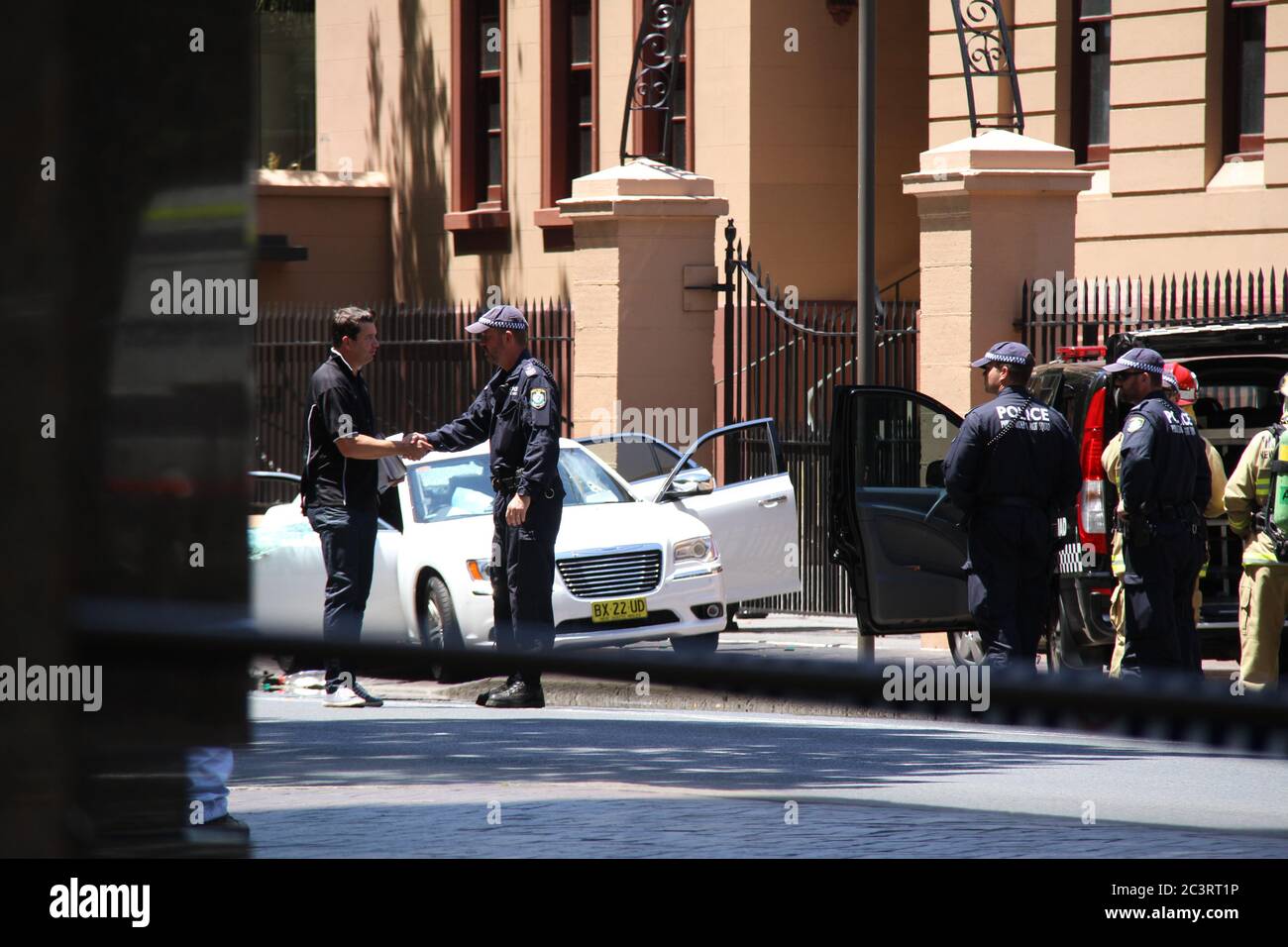 Polizia e soccorso antincendio assistono all'incidente che coinvolge un uomo in una macchina bianca fuori dal Parlamento del NSW su Macquarie Street, Sydney. Foto Stock