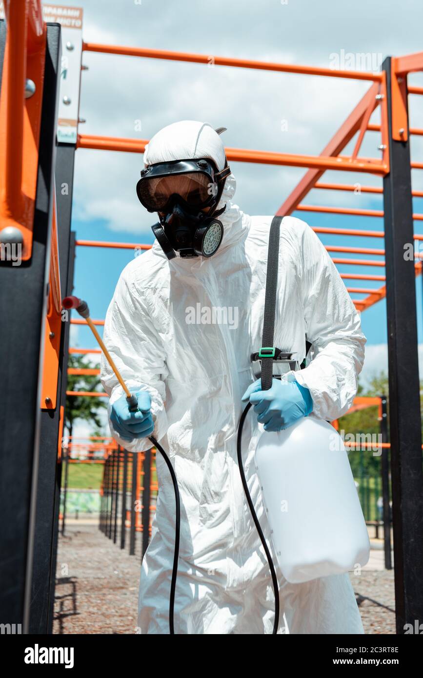 specialista in tuta e respiratore disinfettante per terreni sportivi in parco durante la pandemia covid-19 Foto Stock