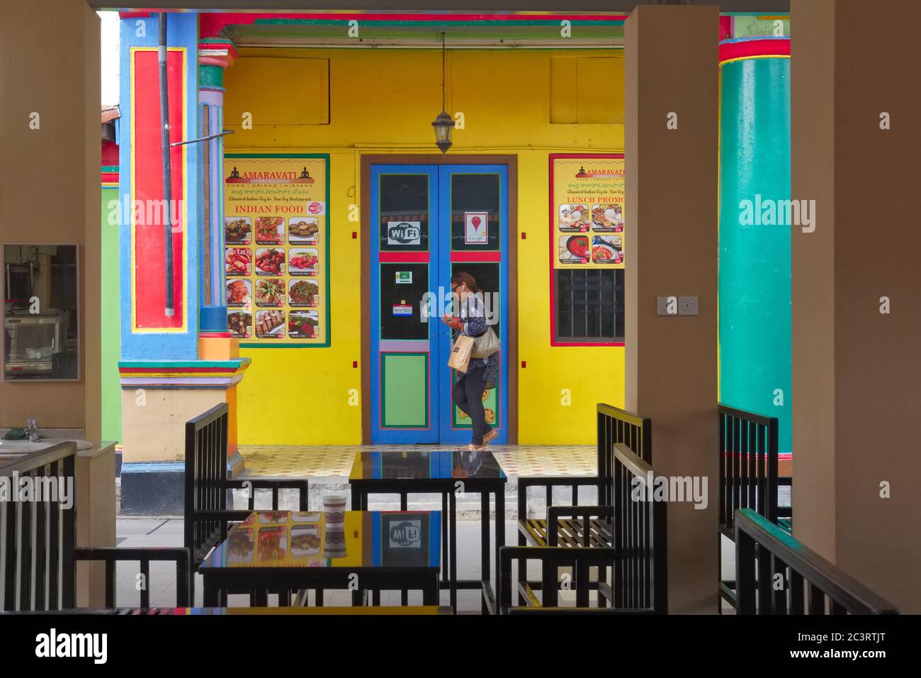 Una donna passa un ristorante indiano multicolore a Curbau Road, Little India, l'area dominata dagli Indiani di Singapore Foto Stock