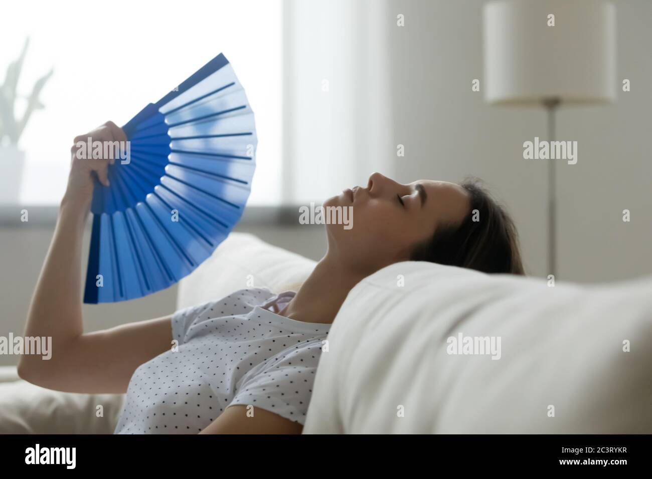 La donna si sente lenta a causa di ondate di calore insopportabili ventilatore che si raffredda Foto Stock