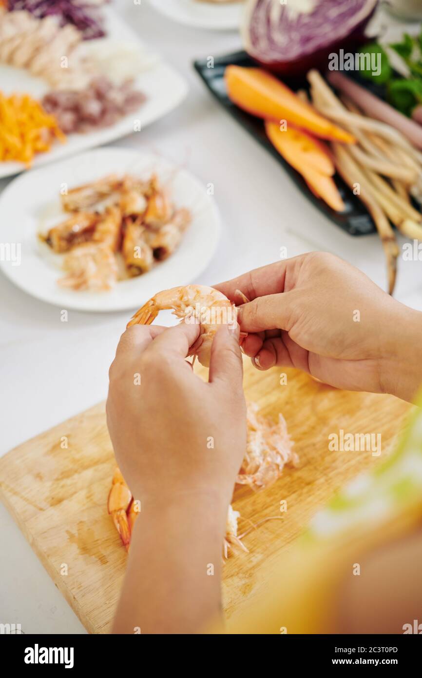Donna che spellano i gamberi cotti quando si preparano involtini primaverili o sushi a casa Foto Stock