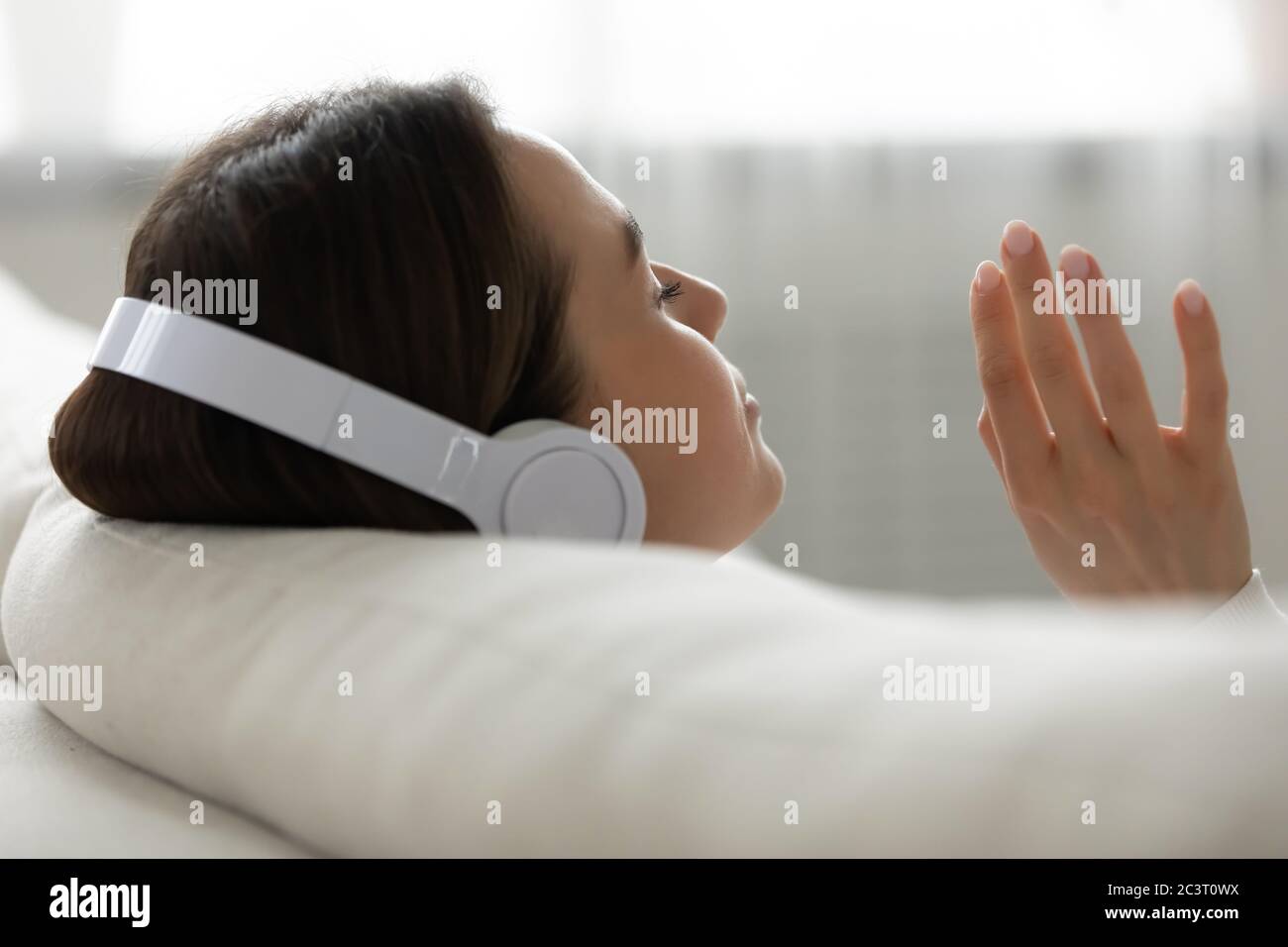 Le cuffie wireless Girl Wear ascoltano la musica a casa immagine di primo piano Foto Stock