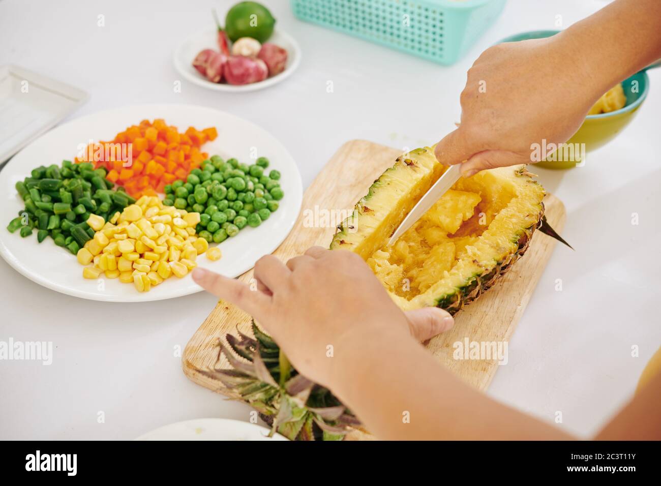 Mani di cuoco che fanno ciotola fuori dell'ananas per riempirlo con le verdure e il riso marrone Foto Stock