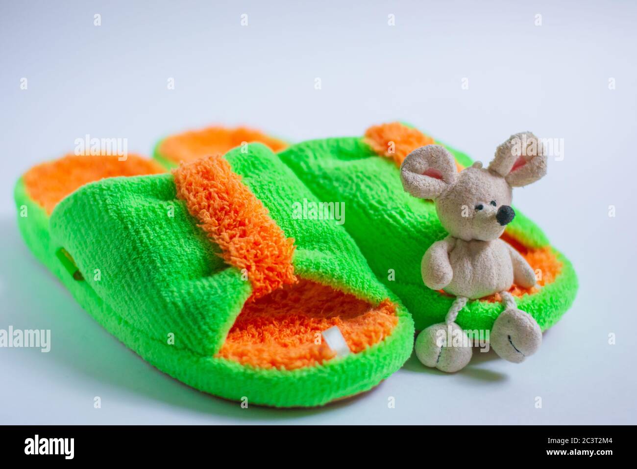 Un mouse giocattolo si trova su pantofole lucide e morbide, isolate su uno sfondo bianco. Casa donne o bambini's abbigliamento.il concetto di calore e comfort casa Foto Stock