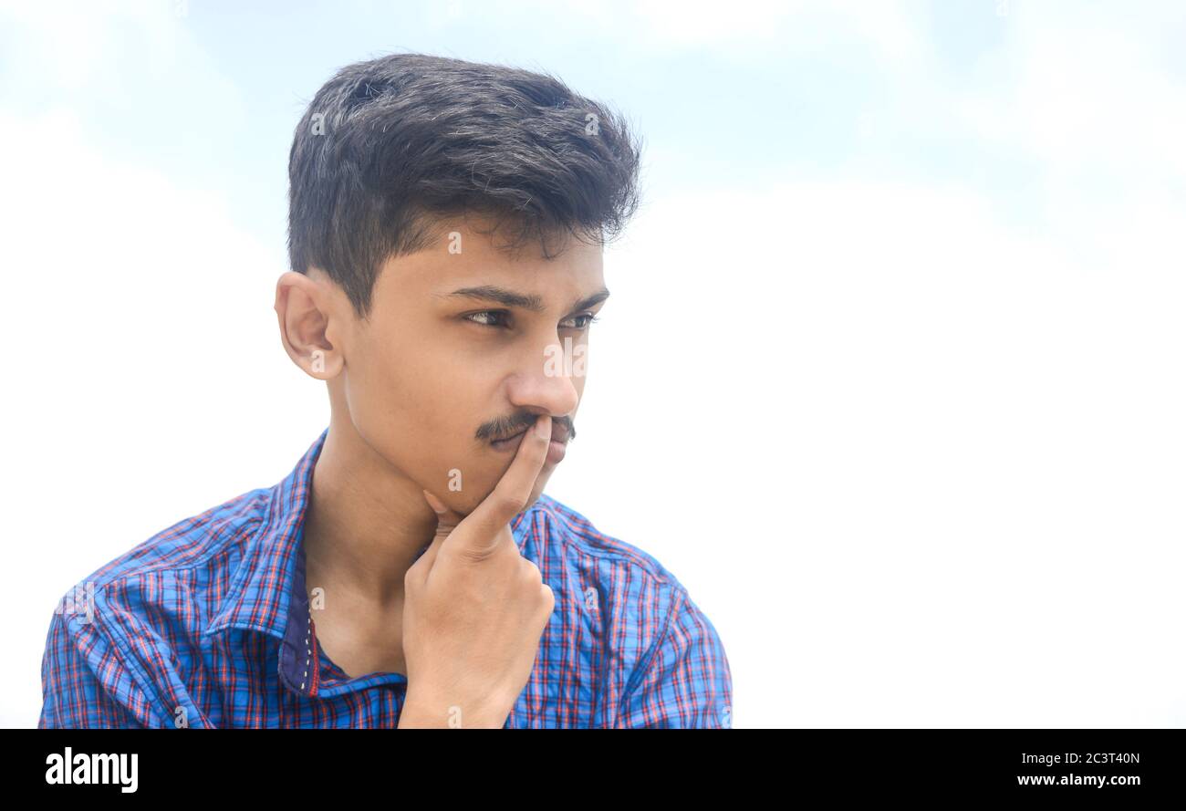 Ritratto di bel giovane uomo teen nel profondo pensare al suo futuro su sfondo cielo. Foto Stock