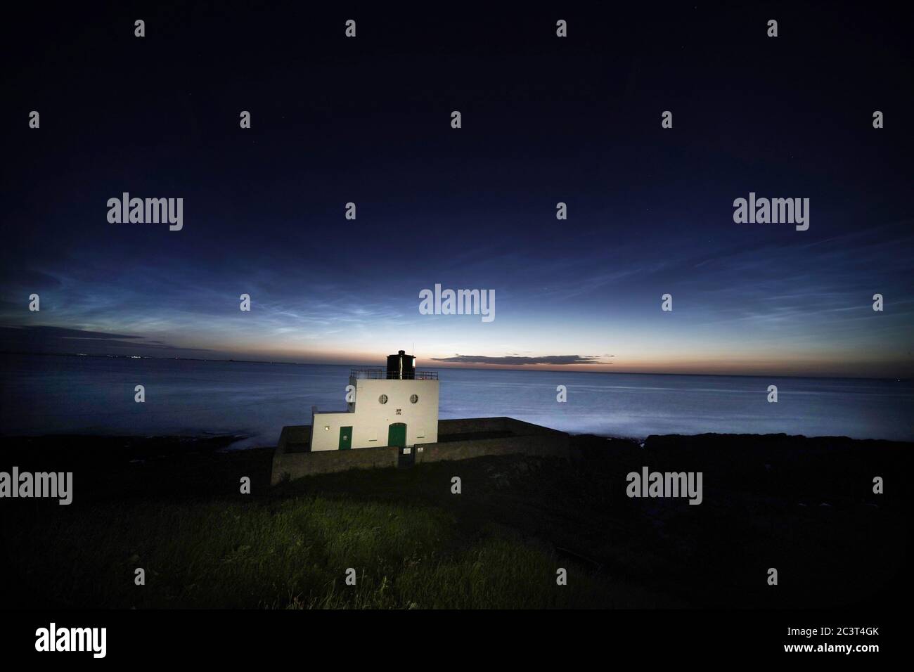 Nuvole Noctilucenti o nuvole notturne che si formano sul faro di Bamburgh in Northumberland. Le nuvole appaiono quando il sole è 6-16 gradi sotto l'orizzonte. Foto Stock