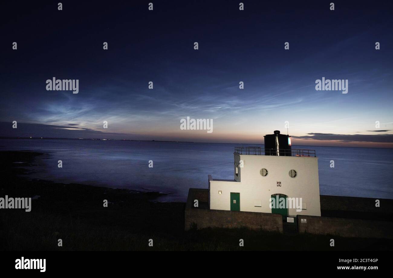 Nuvole Noctilucenti o nuvole notturne che si formano sul faro di Bamburgh in Northumberland. Le nuvole appaiono quando il sole è 6-16 gradi sotto l'orizzonte. Foto Stock