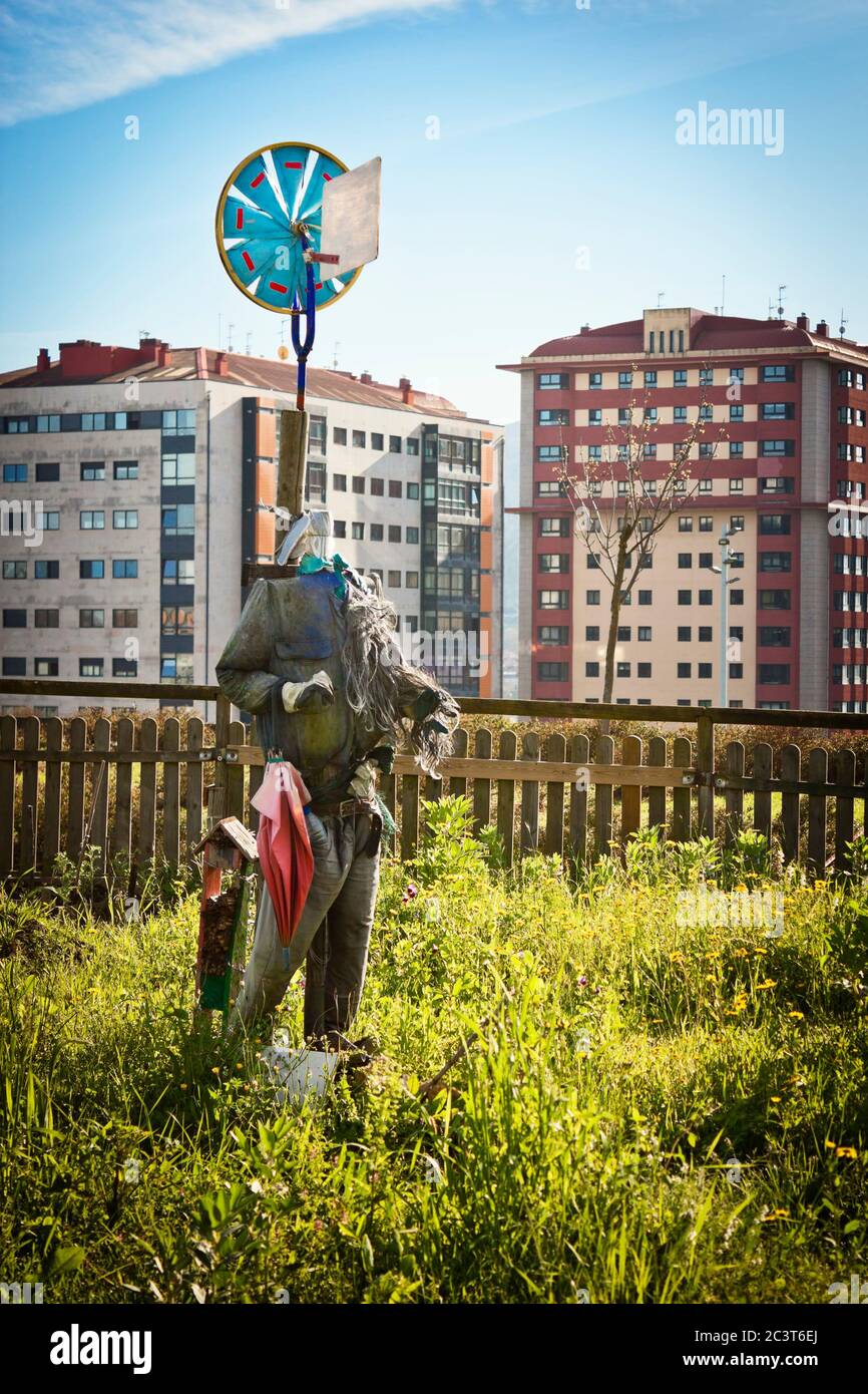 Grunge scarrecrow e vento vento tempo paletta in un giardino urbano pubblico. Edifici cittadini sullo sfondo. Foto Stock