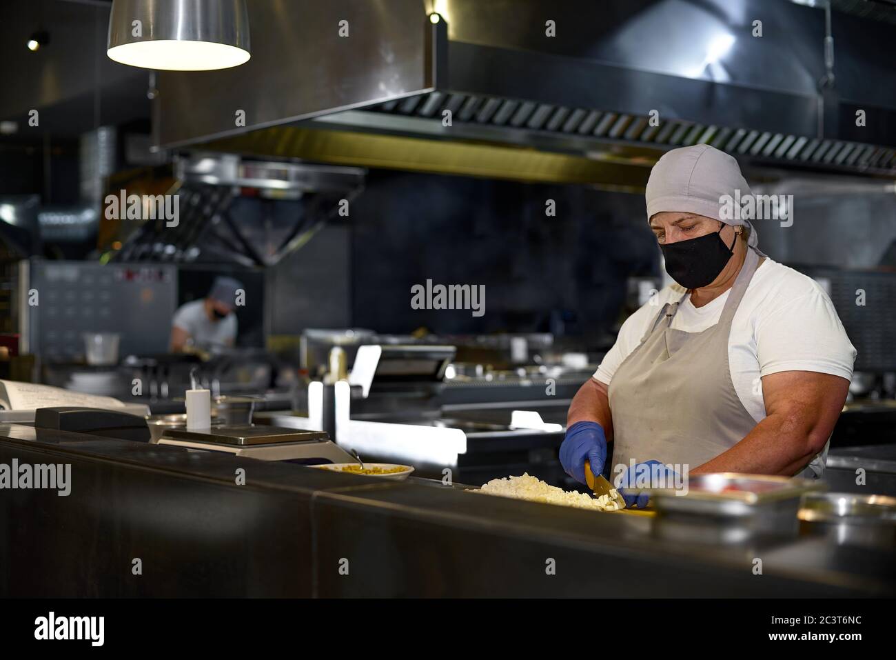 cucina, professione e concetto di gente - donna in età chef indossare  maschera nera protettiva sul viso mentre lavora in cucina ristorante Foto  stock - Alamy