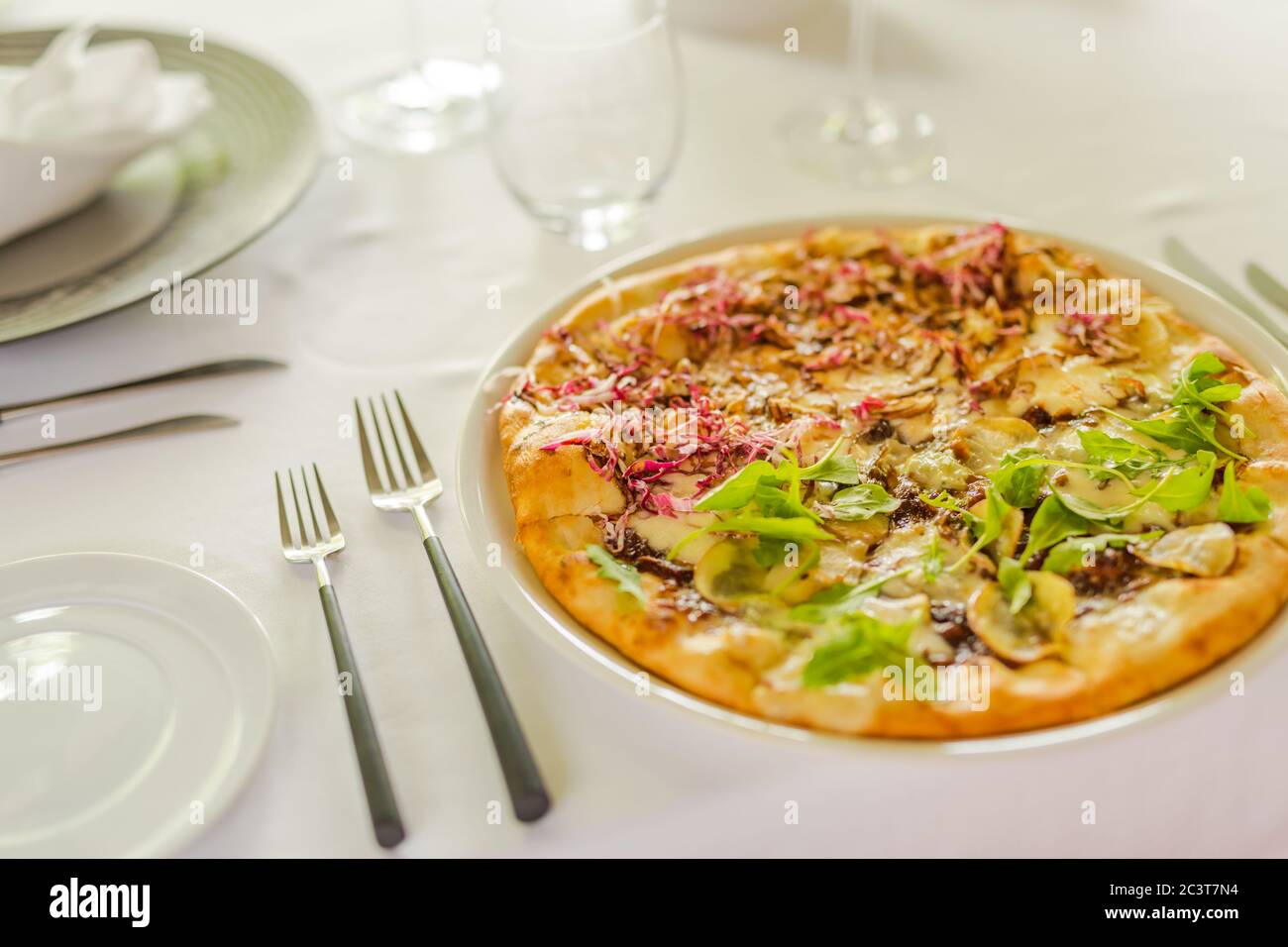 Pizza tradizionale italiana in pizzeria a Milano. Elegante tavolo bianco allestito in un ristorante di lusso, pizza vegana gourmet Foto Stock