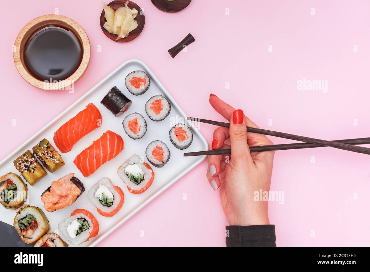 Sushi con salmone su sfondo rosa, vista dall'alto. Foto Stock