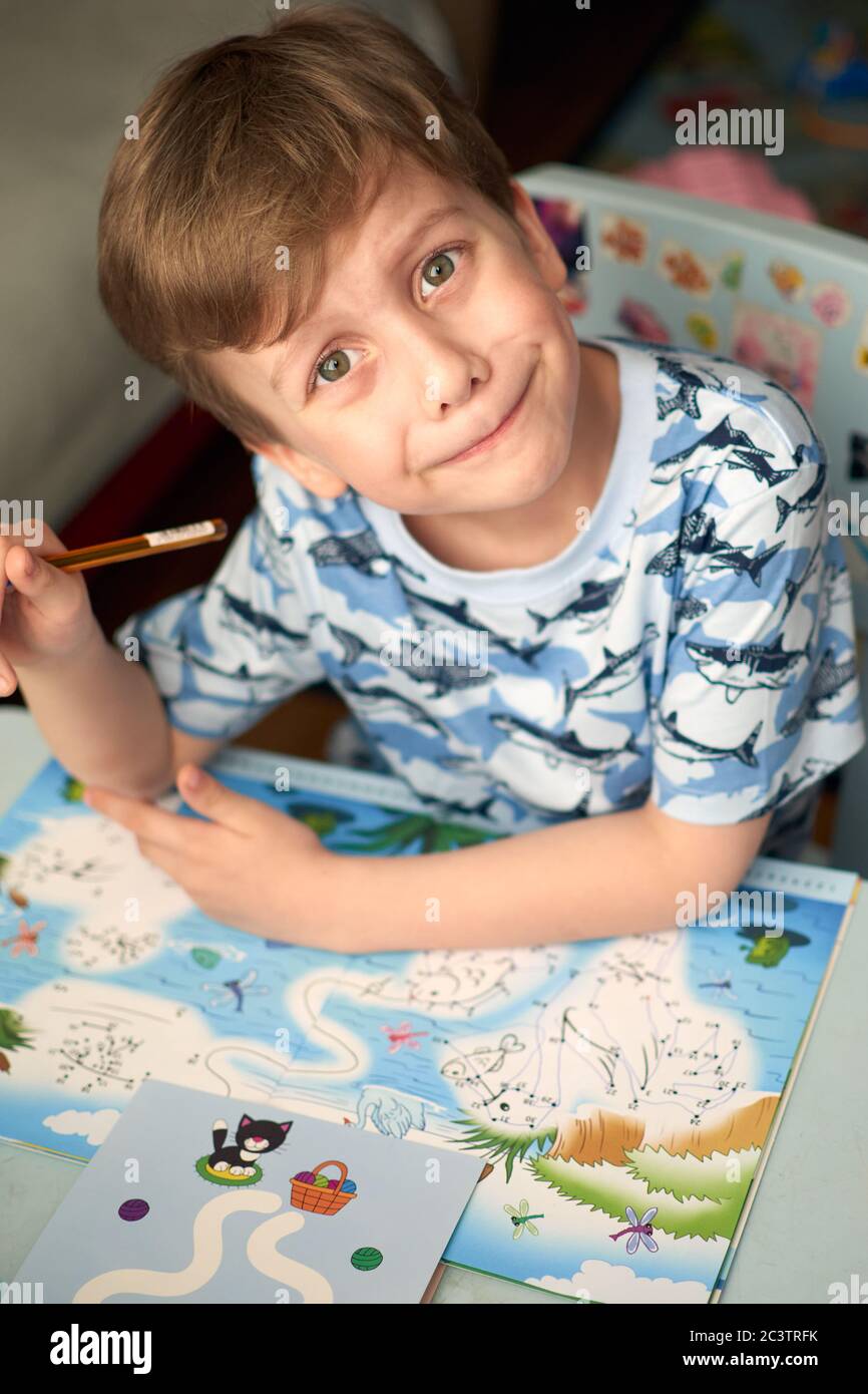 Bambino con compiti durante la lezione online a casa, distanza sociale durante la quarantena Covid-19 Foto Stock