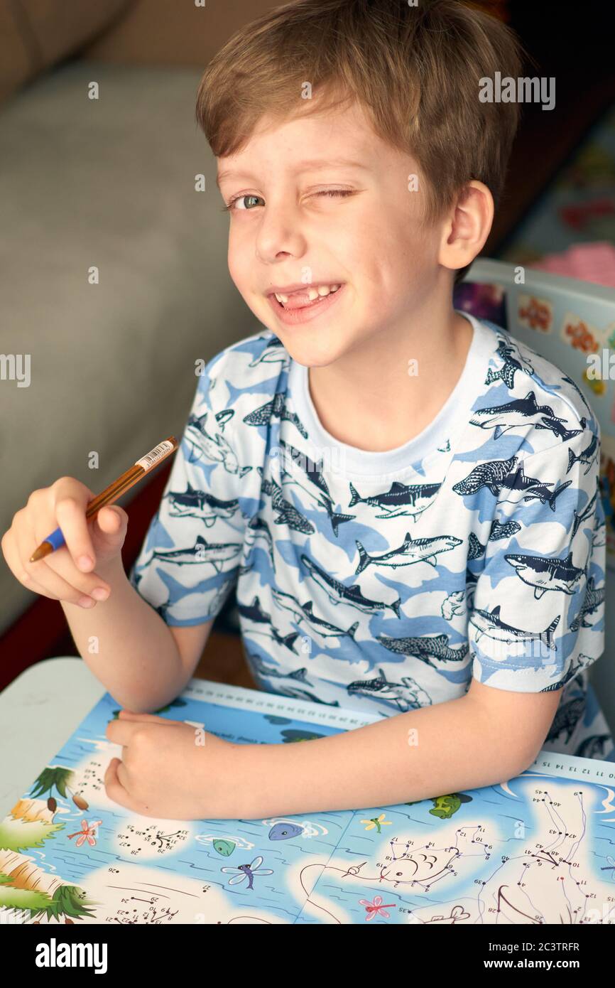 Bambino con compiti durante la lezione online a casa, distanza sociale durante la quarantena Covid-19 Foto Stock