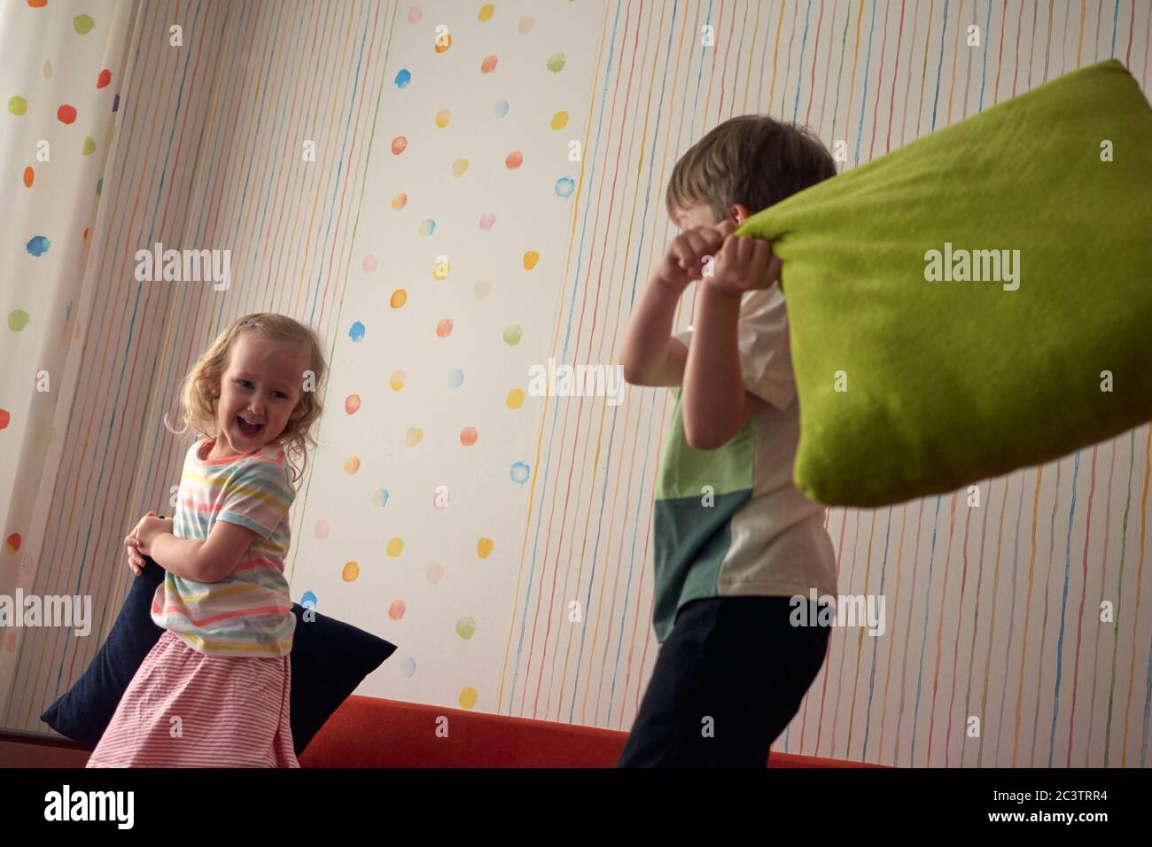 Due bambini felici, ragazzo e ragazza, hanno una lotta cuscino a casa. Divertimento per tutta la famiglia. Quarantine covid-19 e chiuso la scuola durante l'epidemia di coronavirus. Foto Stock