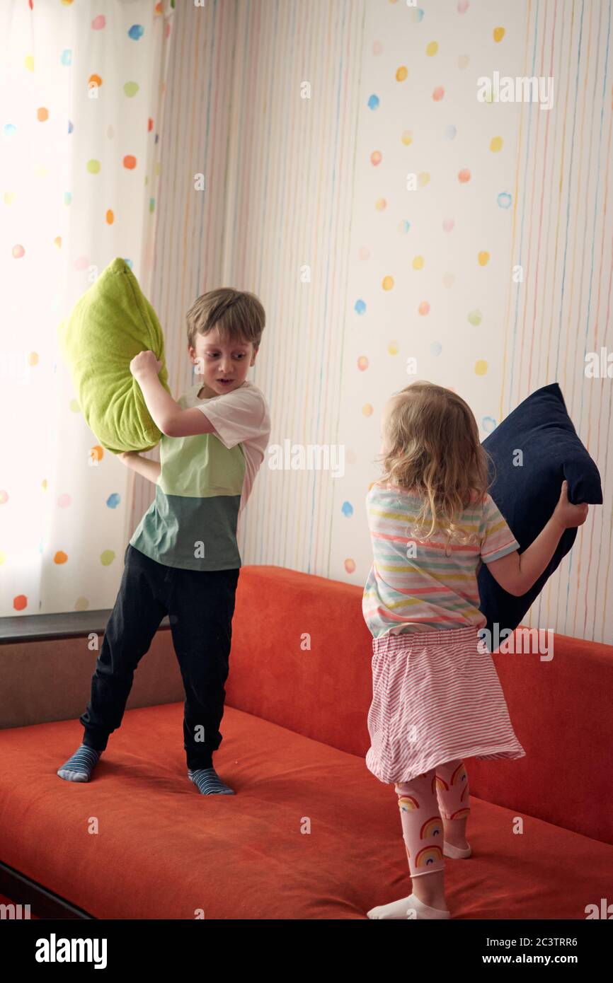 Due bambini felici, ragazzo e ragazza, hanno una lotta cuscino a casa. Divertimento per tutta la famiglia. Quarantine covid-19 e chiuso la scuola durante l'epidemia di coronavirus. Foto Stock