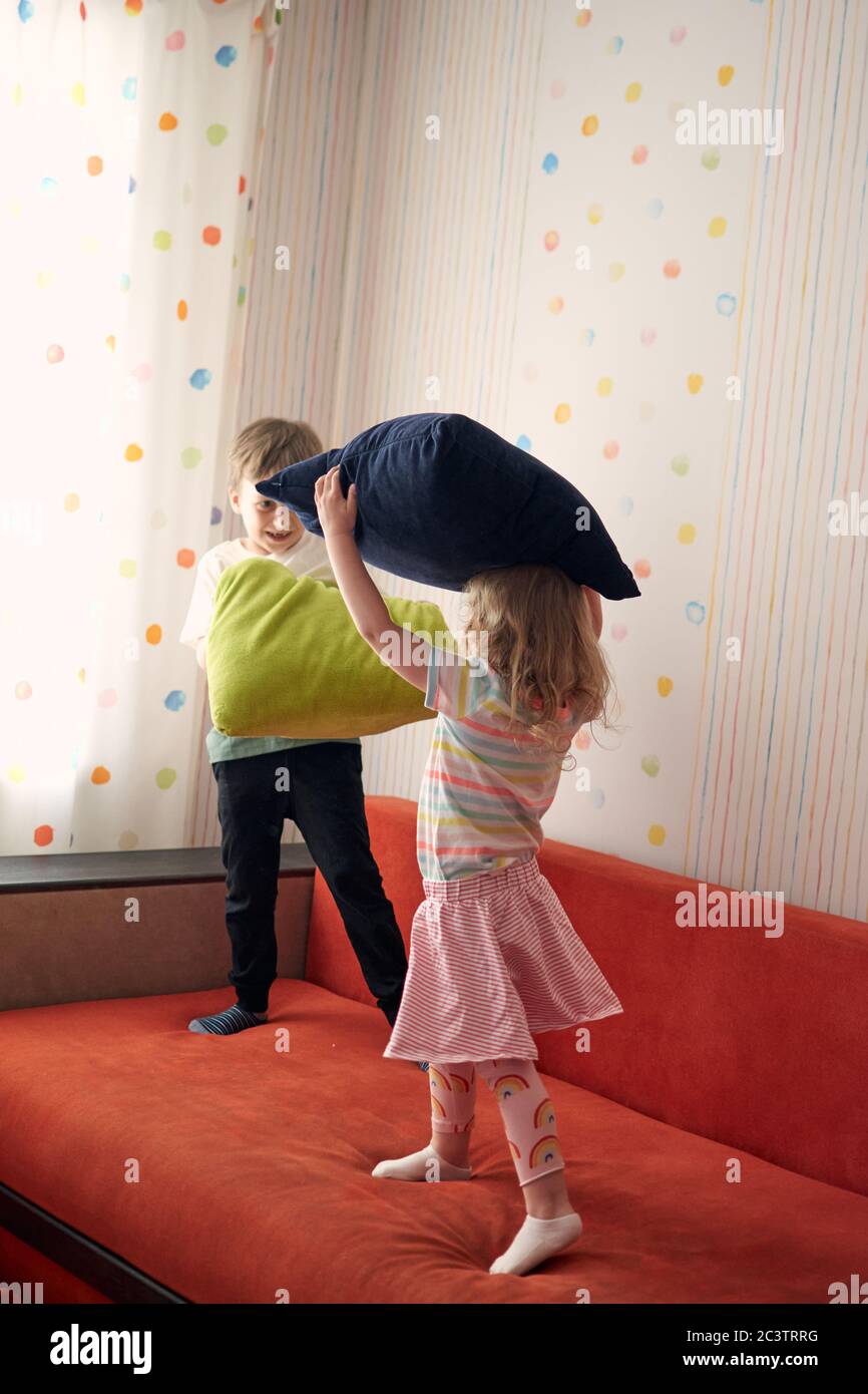 Due bambini felici, ragazzo e ragazza, hanno una lotta cuscino a casa. Divertimento per tutta la famiglia. Quarantine covid-19 e chiuso la scuola durante l'epidemia di coronavirus. Foto Stock