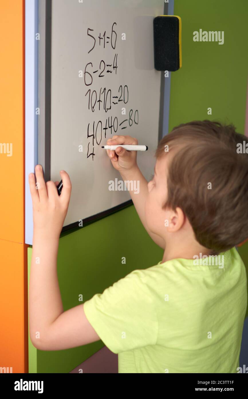 Bambino con compiti durante la lezione di matematica online a casa, distanza sociale durante la quarantena Covid-19 Foto Stock