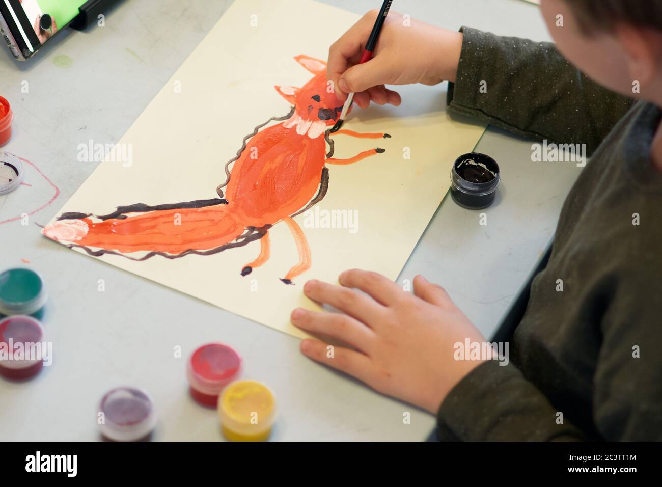 Bambino annuce una foto durante la lezione di arte on-line al telefono cellulare, distanza sociale durante la quarantena Covid-19 Foto Stock