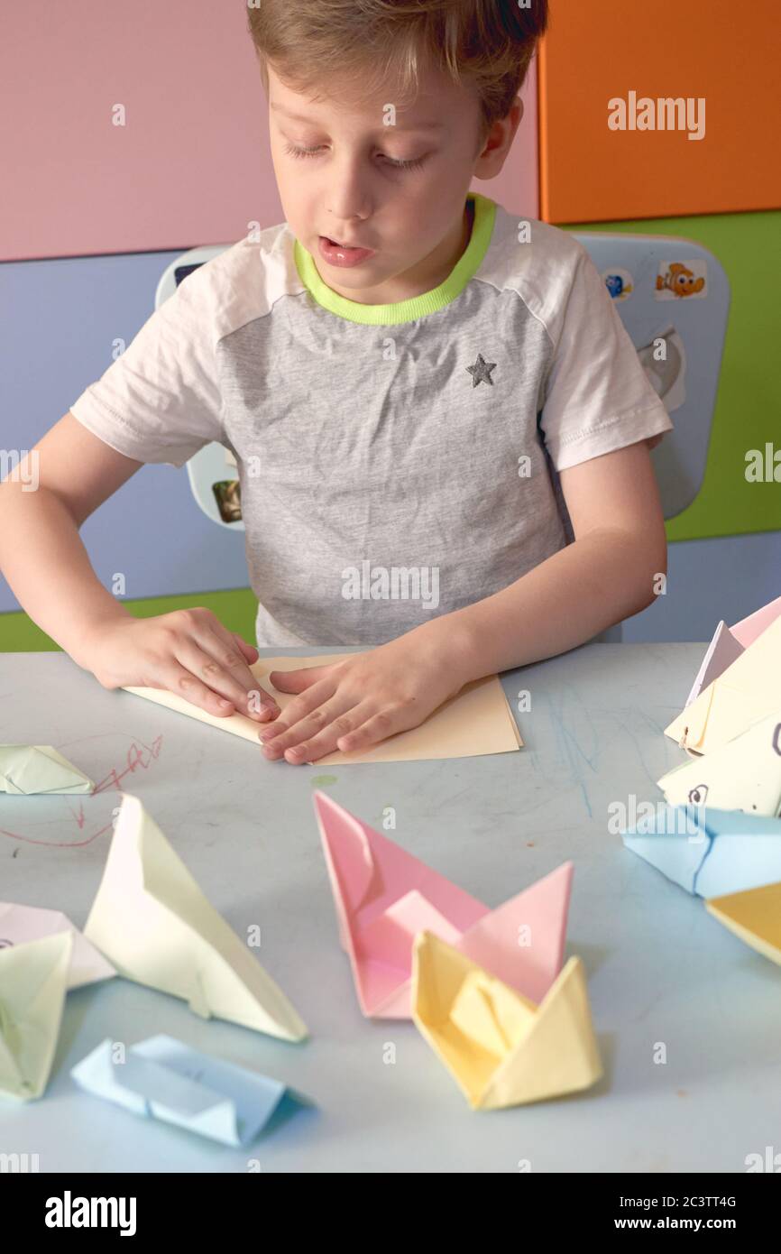 6 anni ragazzo fa un origami aerei e rane durante la quarantena Covid-19 Foto Stock