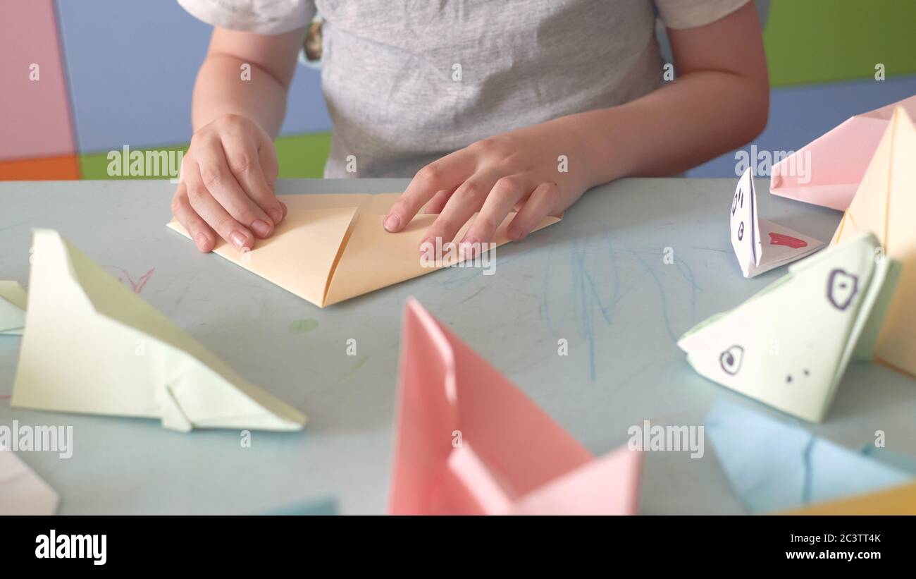 6 anni ragazzo fa un origami aerei e rane durante la quarantena Covid-19 Foto Stock