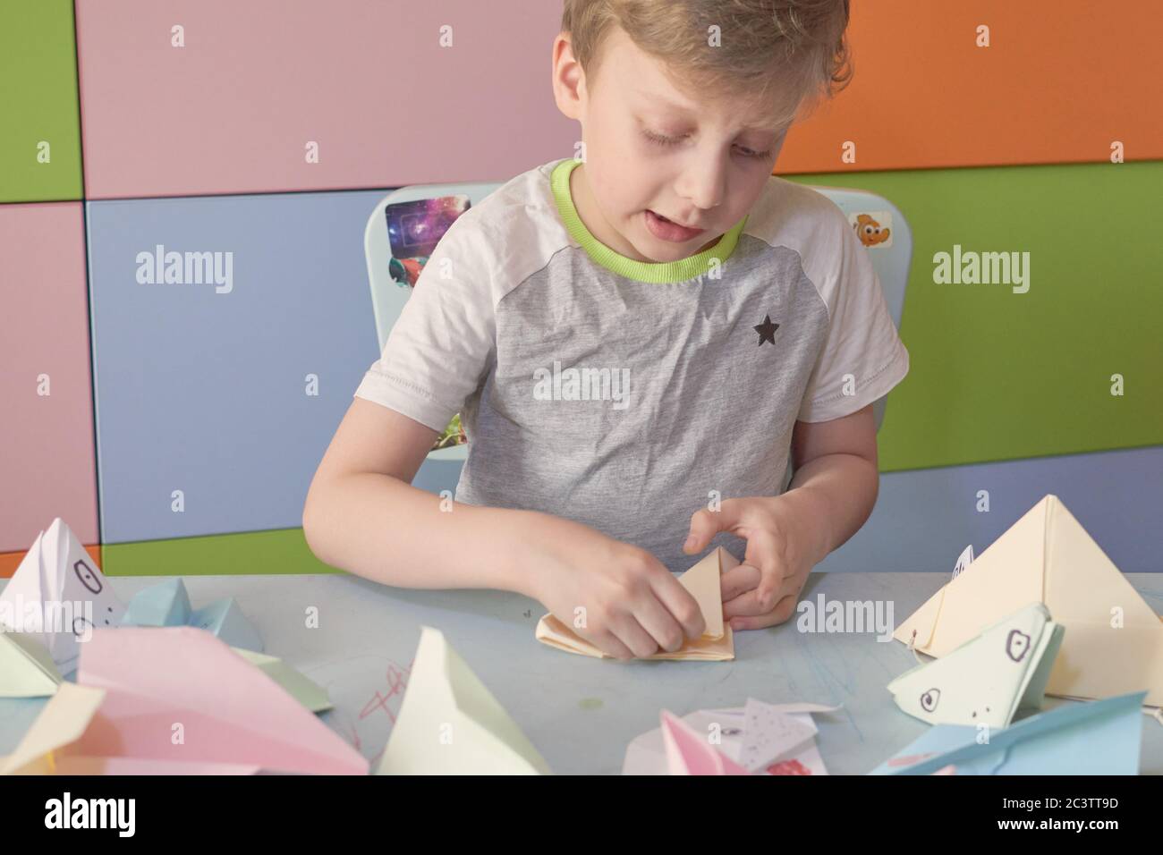 6 anni ragazzo fa un origami aerei e rane durante la quarantena Covid-19 Foto Stock